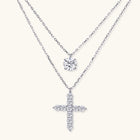 Two delicate sterling silver necklaces with moissanite stones - one solitaire pendant and one cross pendant on white background.